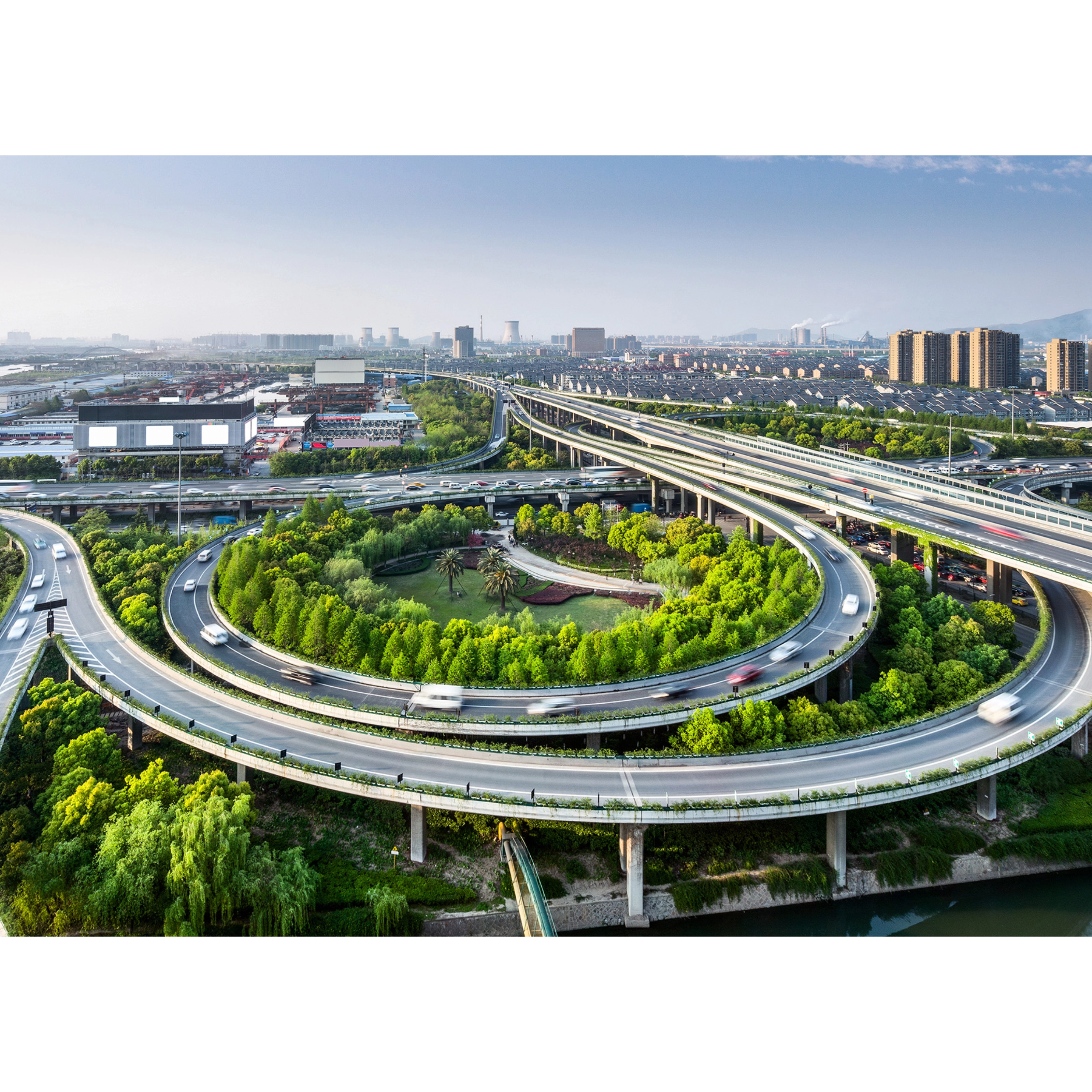 Large highway interchange with loop ramps and green areas in an urban cityscape.