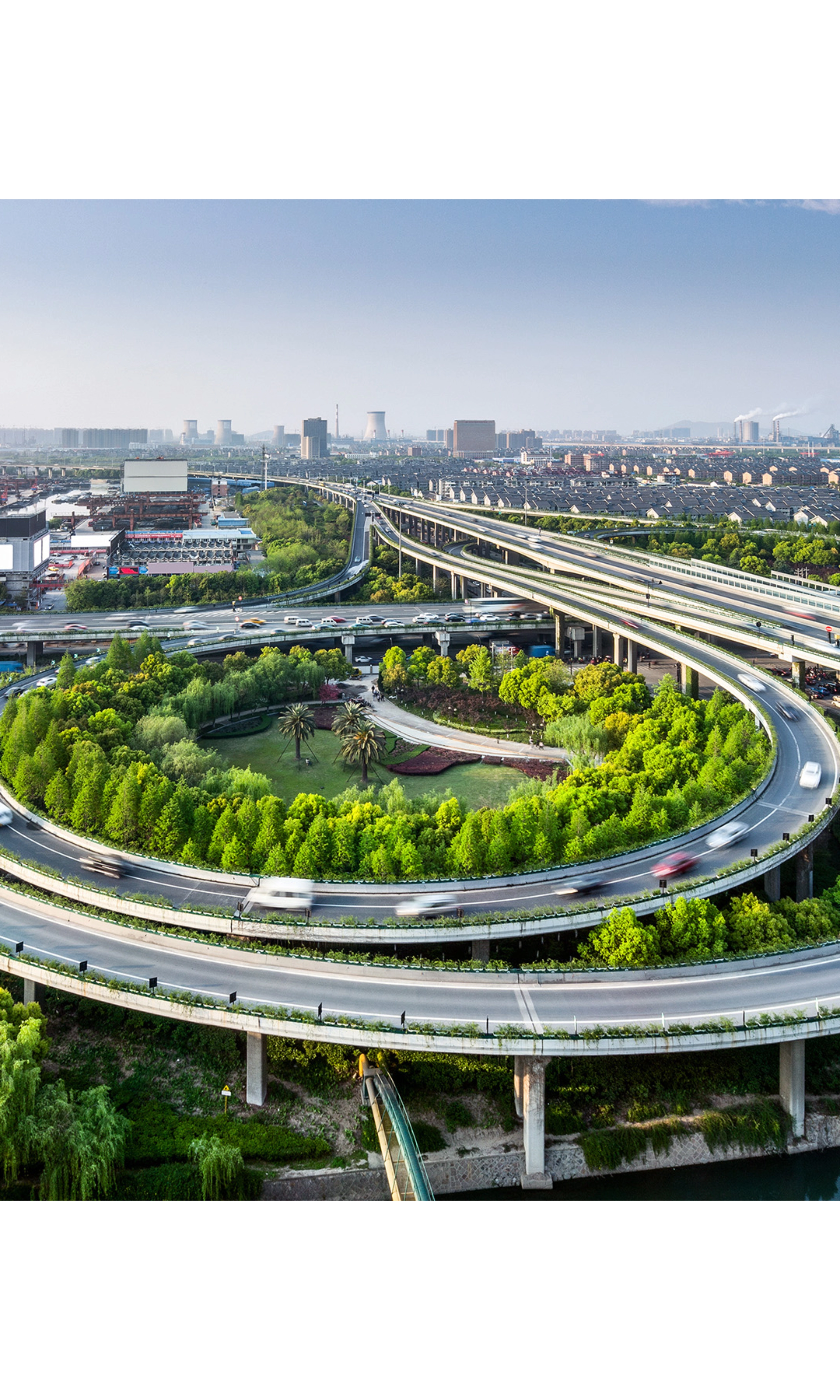 Large highway interchange with loop ramps and green areas in an urban cityscape.