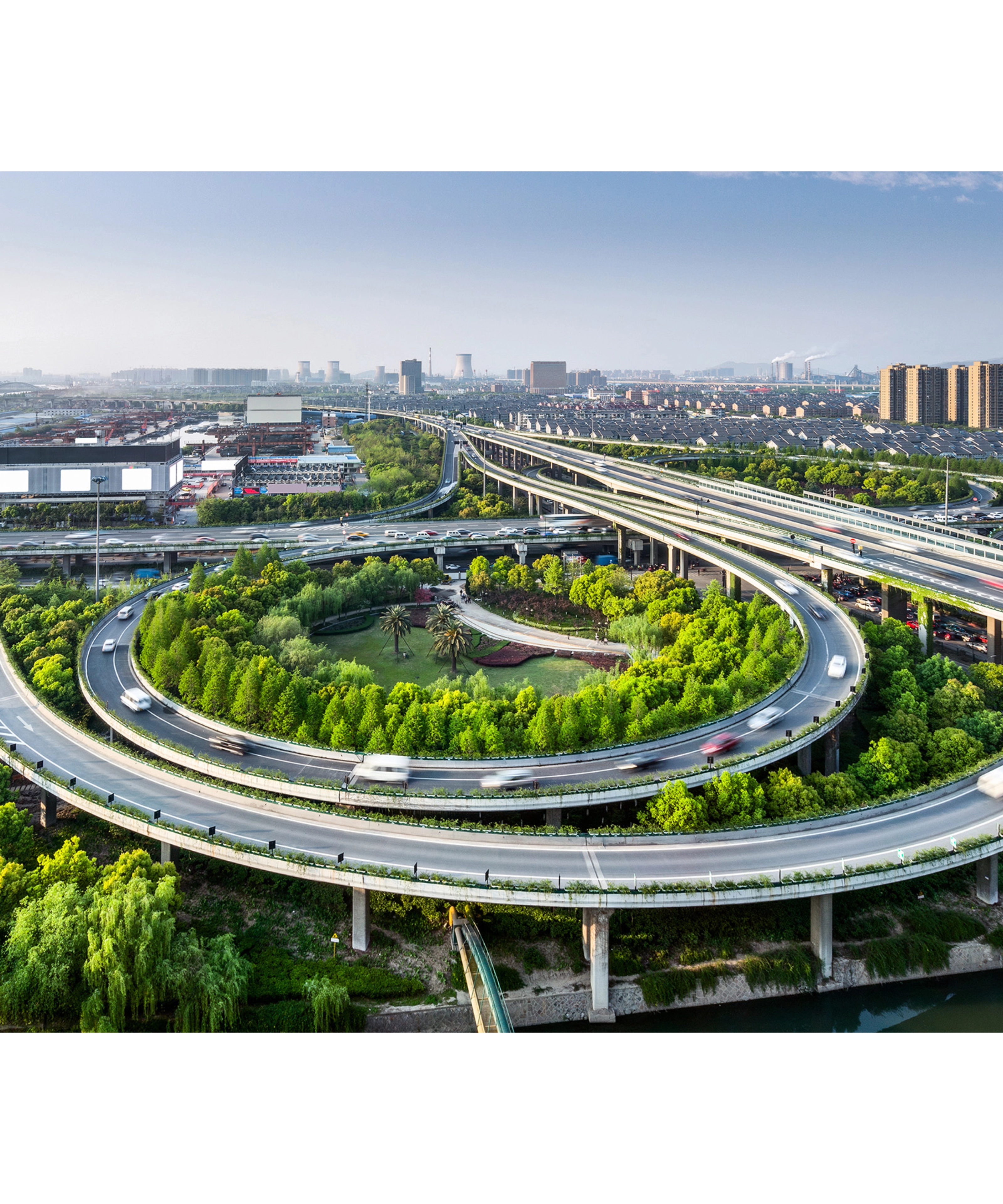 Large highway interchange with loop ramps and green areas in an urban cityscape.