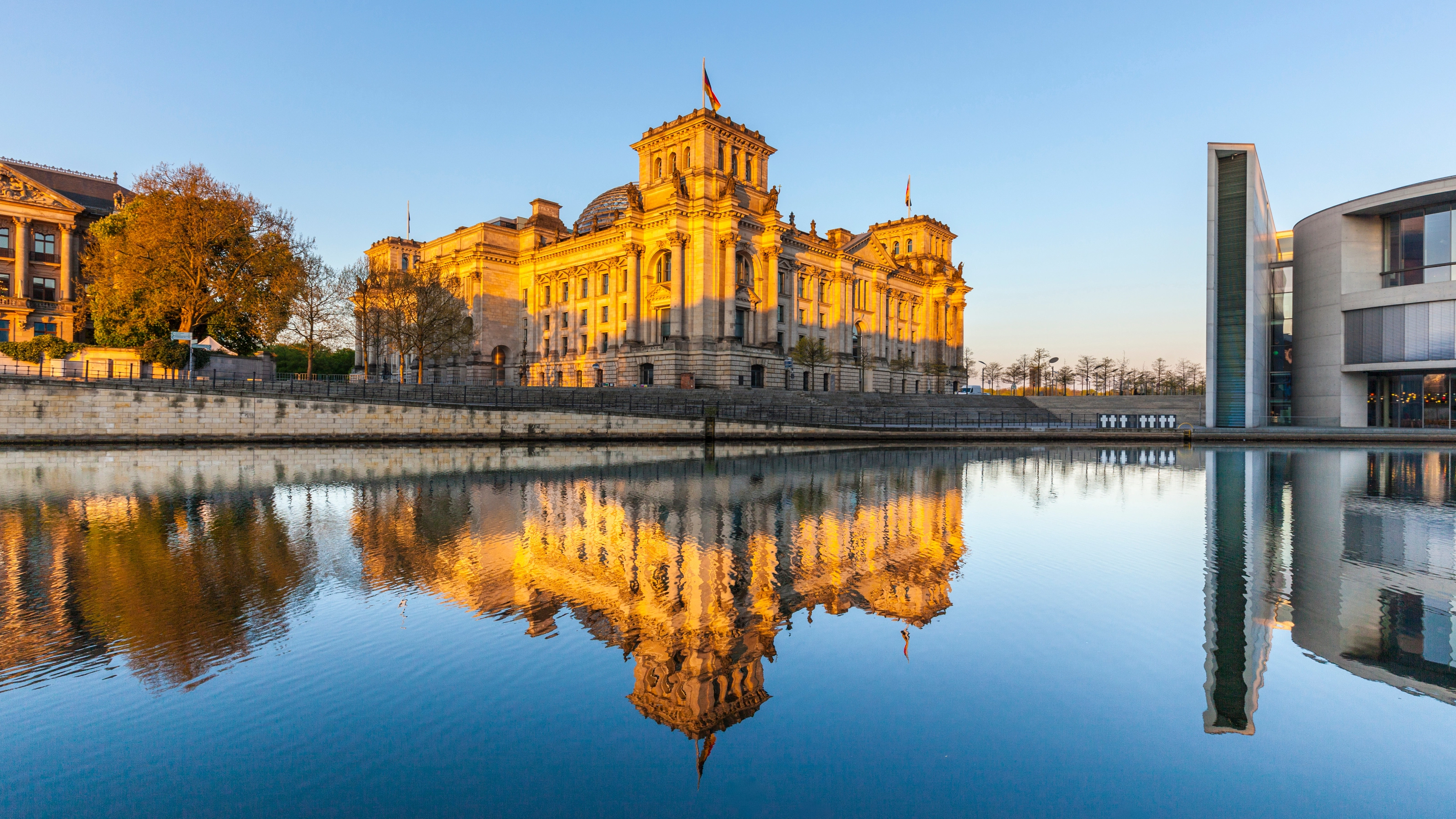 The German Reichstag building in Berlin, reflected in the river at sunset.