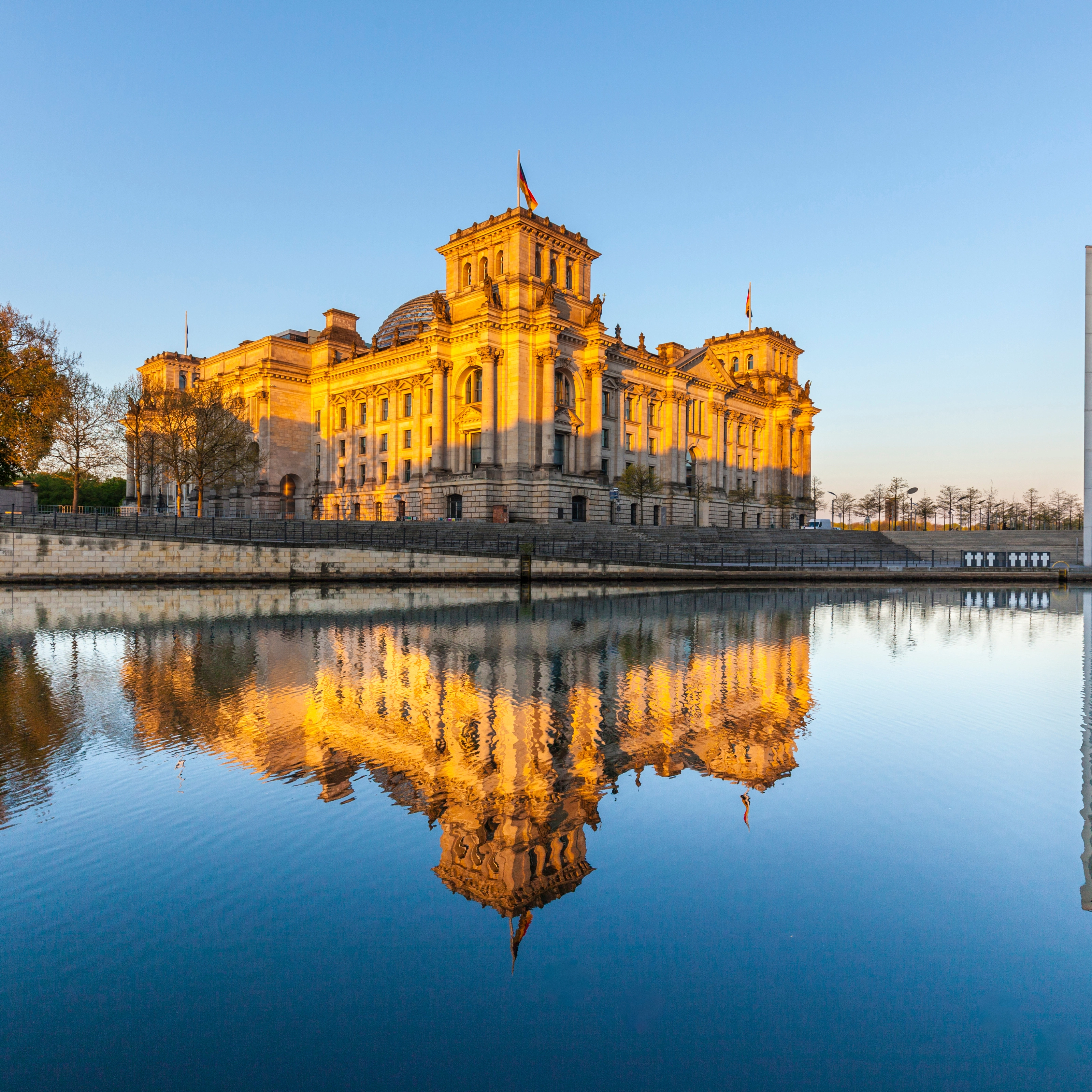 The German Reichstag building in Berlin, reflected in the river at sunset.