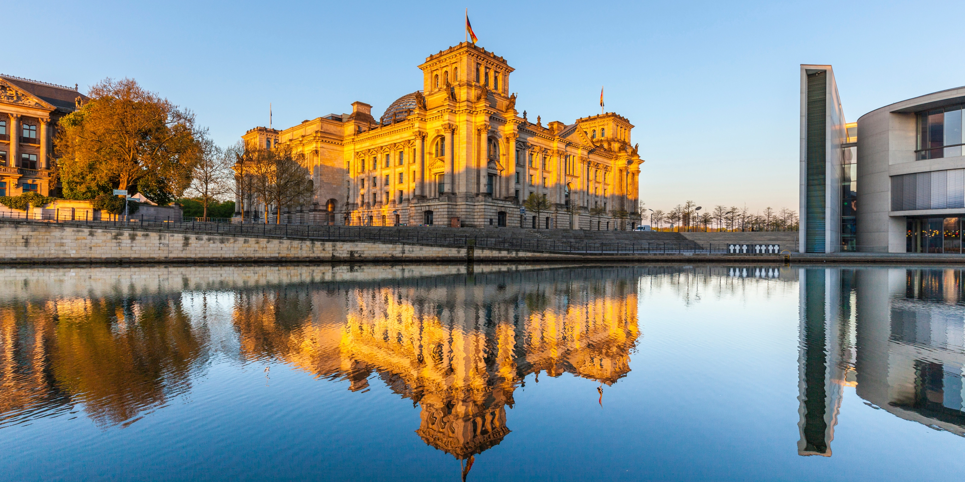 The German Reichstag building in Berlin, reflected in the river at sunset.