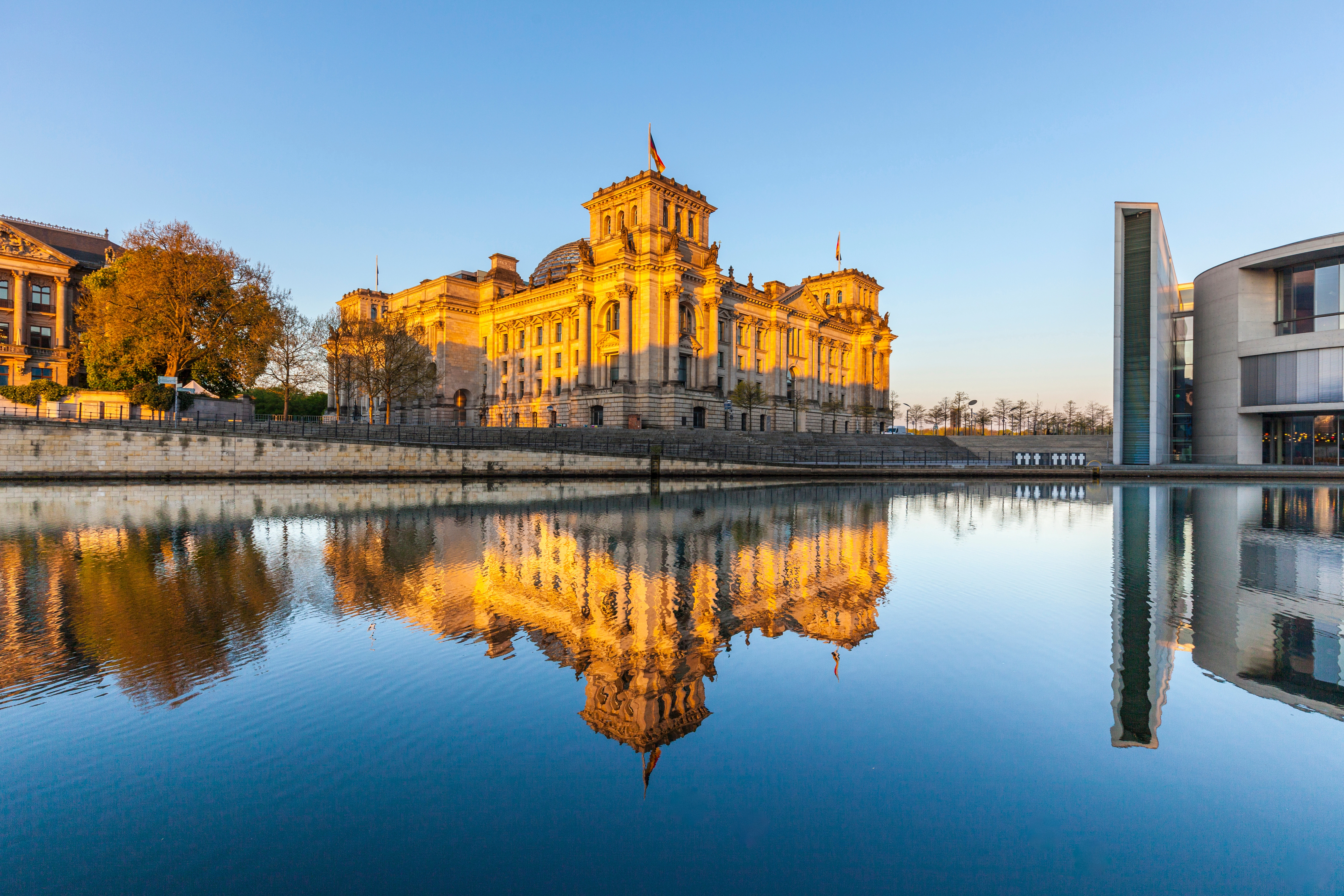 The German Reichstag building in Berlin, reflected in the river at sunset.