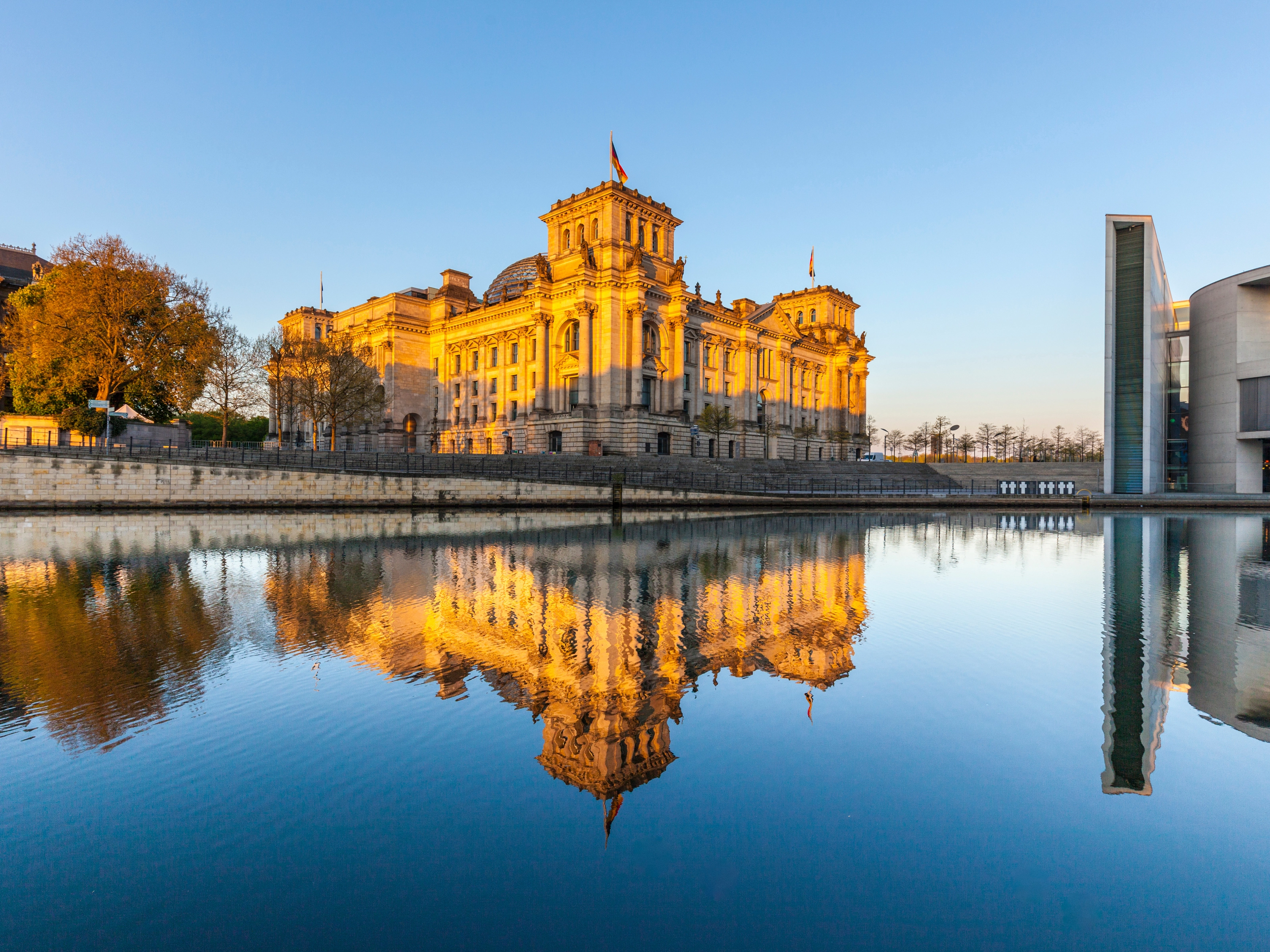 The German Reichstag building in Berlin, reflected in the river at sunset.