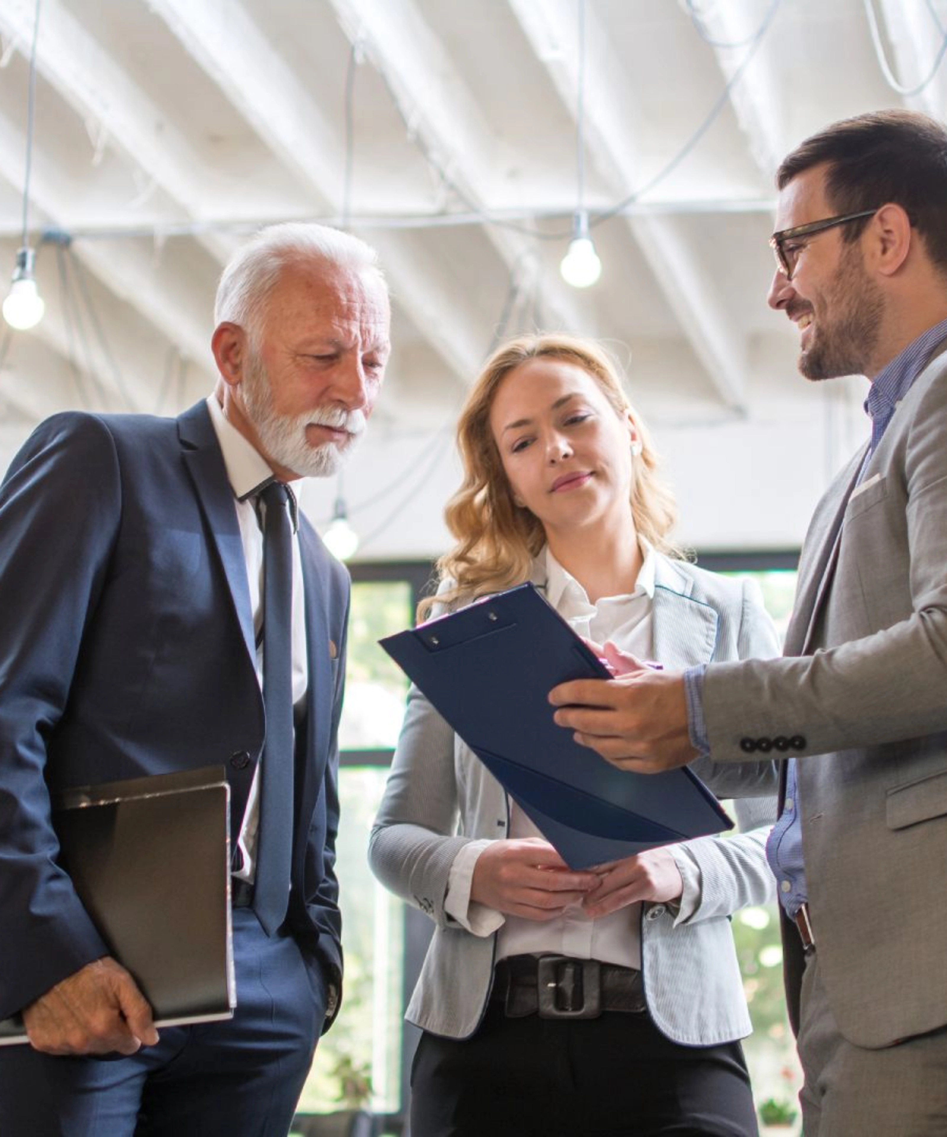 Drei Personen im Business-Outfit besprechen gemeinsam ein Dokument in einem modernen Büro.
